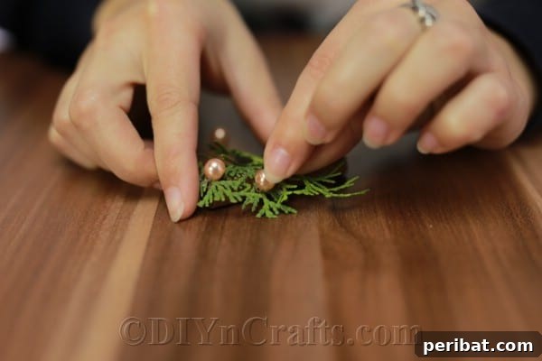 Infuse Your Tree with Rustic Aroma: DIY Ornaments 9 Close-up of faux pearls being glued onto the rustic pine sprig ornament.