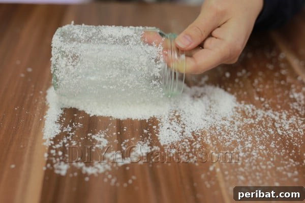 The frosted glass jar, now coated with artificial snow, ready for decorative embellishments.