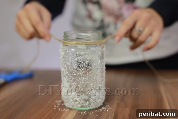 Twine being wrapped around the neck of the frosted glass jar, adding a rustic decorative element.