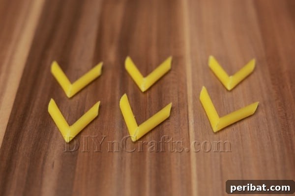Dazzling Pasta Snowflake Christmas Ornaments 15 Creating a chevron shape by gluing two pasta pieces at an angle.