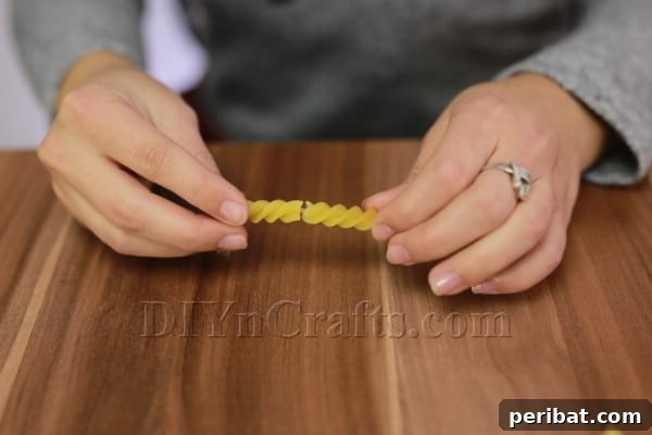 Dazzling Pasta Snowflake Christmas Ornaments 18 Gluing two spiral pasta pieces end-to-end for a longer snowflake arm in Design #3.