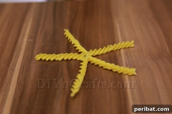 Dazzling Pasta Snowflake Christmas Ornaments 20 The star shape taking form as spiral pasta pieces are glued together at the center.