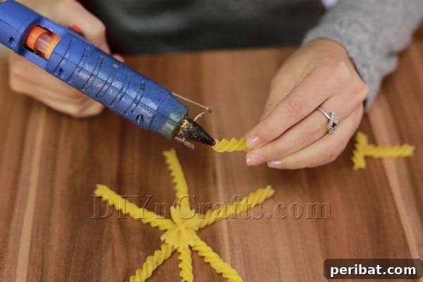 Dazzling Pasta Snowflake Christmas Ornaments 22 Adding single spiral pasta pieces between the main arms of the star for added detail.