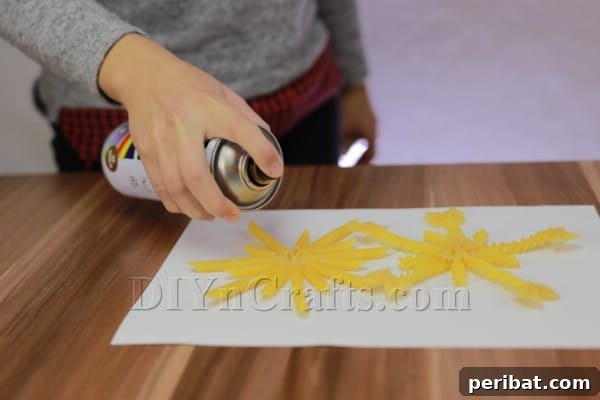 Dazzling Pasta Snowflake Christmas Ornaments 27 Using spray paint to achieve a smooth, even coating on the pasta snowflake ornaments.
