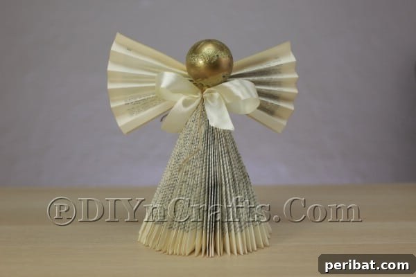 Upcycle an Old Book into a Stunning Christmas Angel 17 Hot gluing the ribbon bow to the angel's neck area