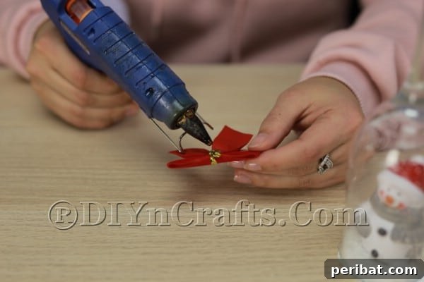 Transform Wine Glasses into Sparkling Christmas Candle Holders 11 Attaching a festive bow to the wine glass stem