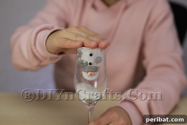 Securing the ornament and cardboard to the wine glass
