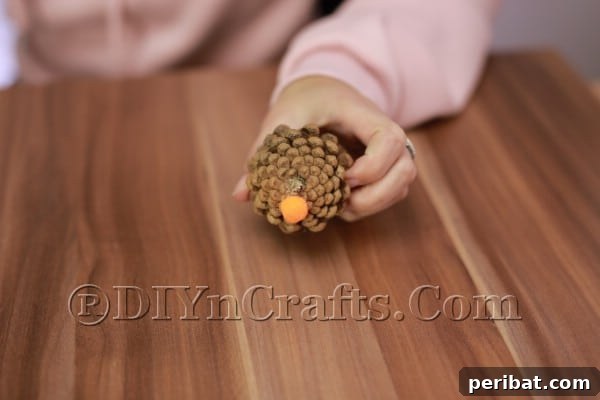 Step 4: Attach pom-pom nose to pine cone