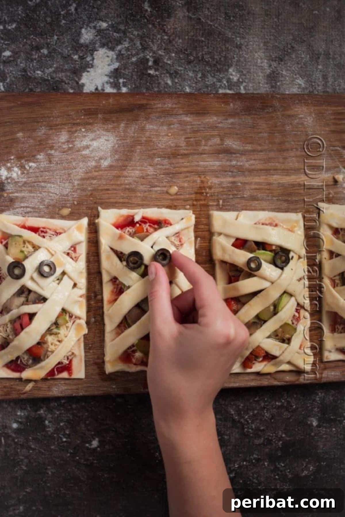 Spooktacular Mummy Pizzas 6 Adding mummy eyes.