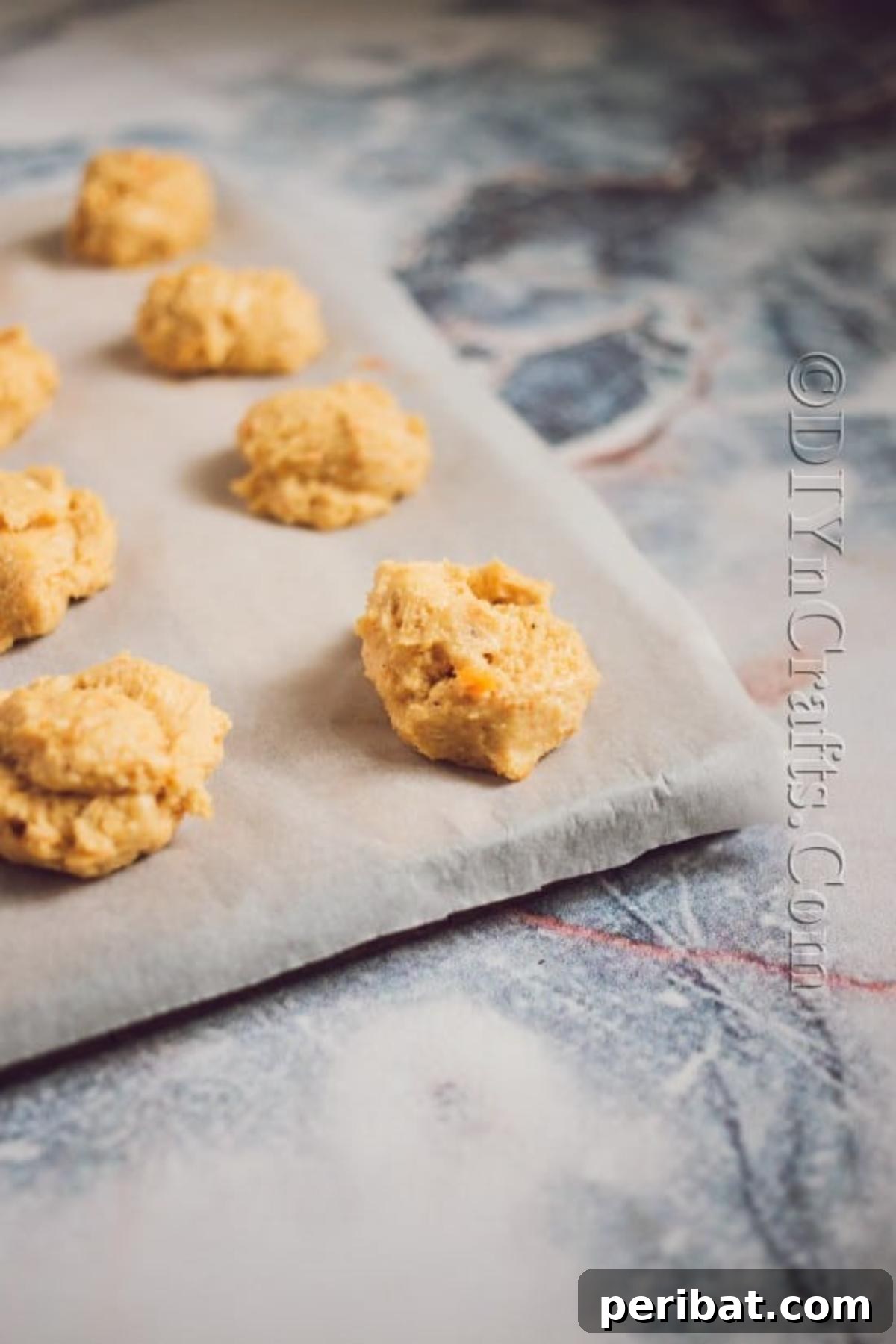 Cozy Fall Pumpkin Cookies Recipe 6 Raw pumpkin cookie dough dropped onto a parchment-lined baking sheet, spaced out and ready for the oven.