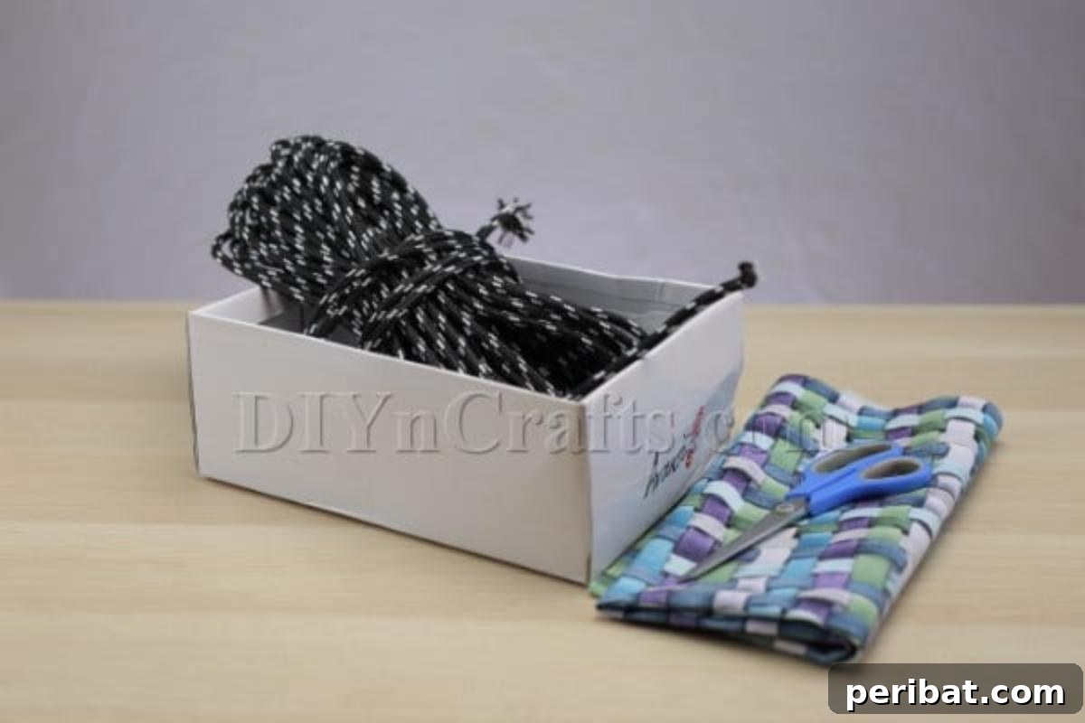 Cardboard Box Makeover: Create a Stylish Storage Basket 3 Materials for the storage box project, including a cardboard box, fabric, rope, and a hot glue gun.