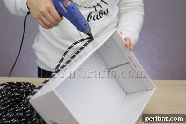 Cardboard Box Makeover: Create a Stylish Storage Basket 6 The initial rows of rope being glued to the cardboard box's base.
