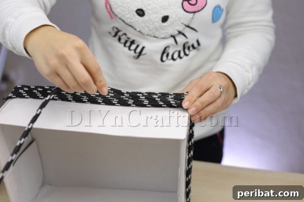 Cardboard Box Makeover: Create a Stylish Storage Basket 7 Continuing to wrap rope around the box, moving upwards.