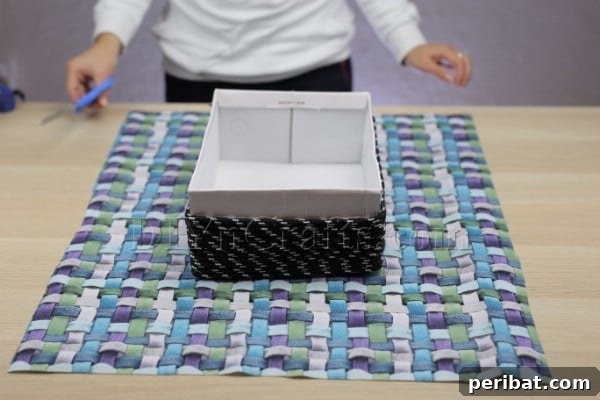 Cardboard Box Makeover: Create a Stylish Storage Basket 10 Measuring and cutting fabric to fit inside and over the edges of the box.