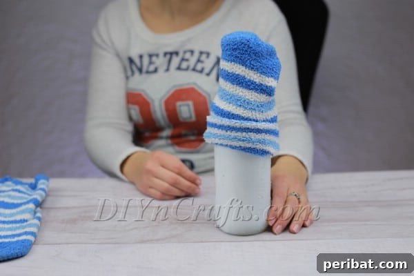 Fitting a rolled sock as a festive hat on the bottle snowman