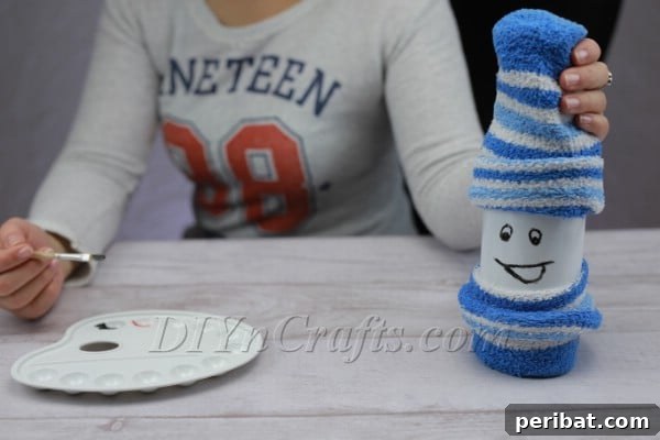 Painting the expressive eyes on the DIY bottle snowman after the mouth has dried