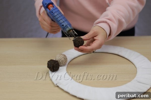 Create A Rustic Cardboard And Yarn Christmas Wreath 10 Attaching a decorative bow to the top of the wreath.
