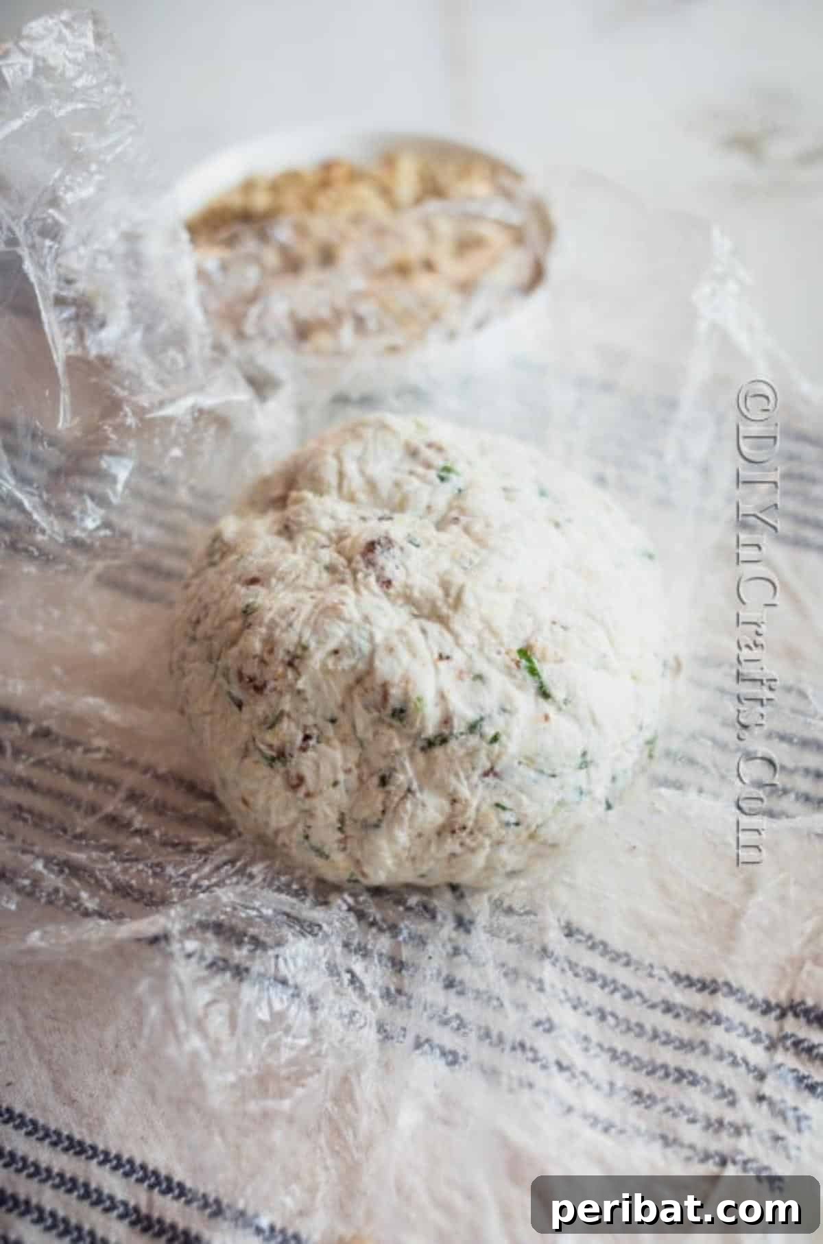 The Ultimate Party Cheese Ball 5 Shaping the cheese mixture into a compact ball using plastic wrap before chilling.
