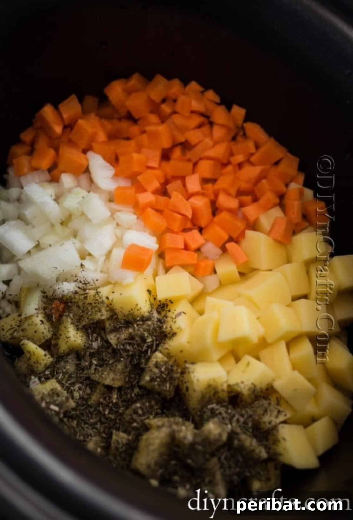 Hearty Family Cheeseburger Soup 4 Freshly chopped onions, potatoes, and carrots being added to a slow cooker, ready for the soup base.