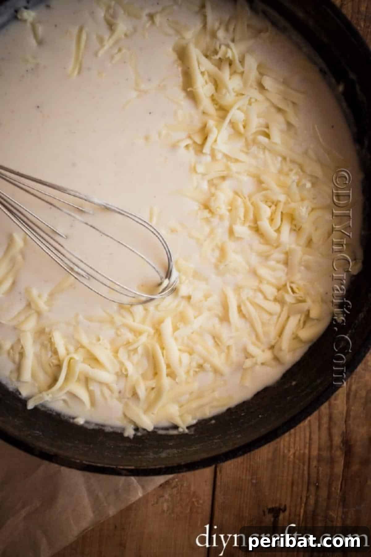 Hearty Family Cheeseburger Soup 6 Shredded sharp cheddar cheese being added to a simmering creamy base, creating the rich sauce for the cheeseburger soup.