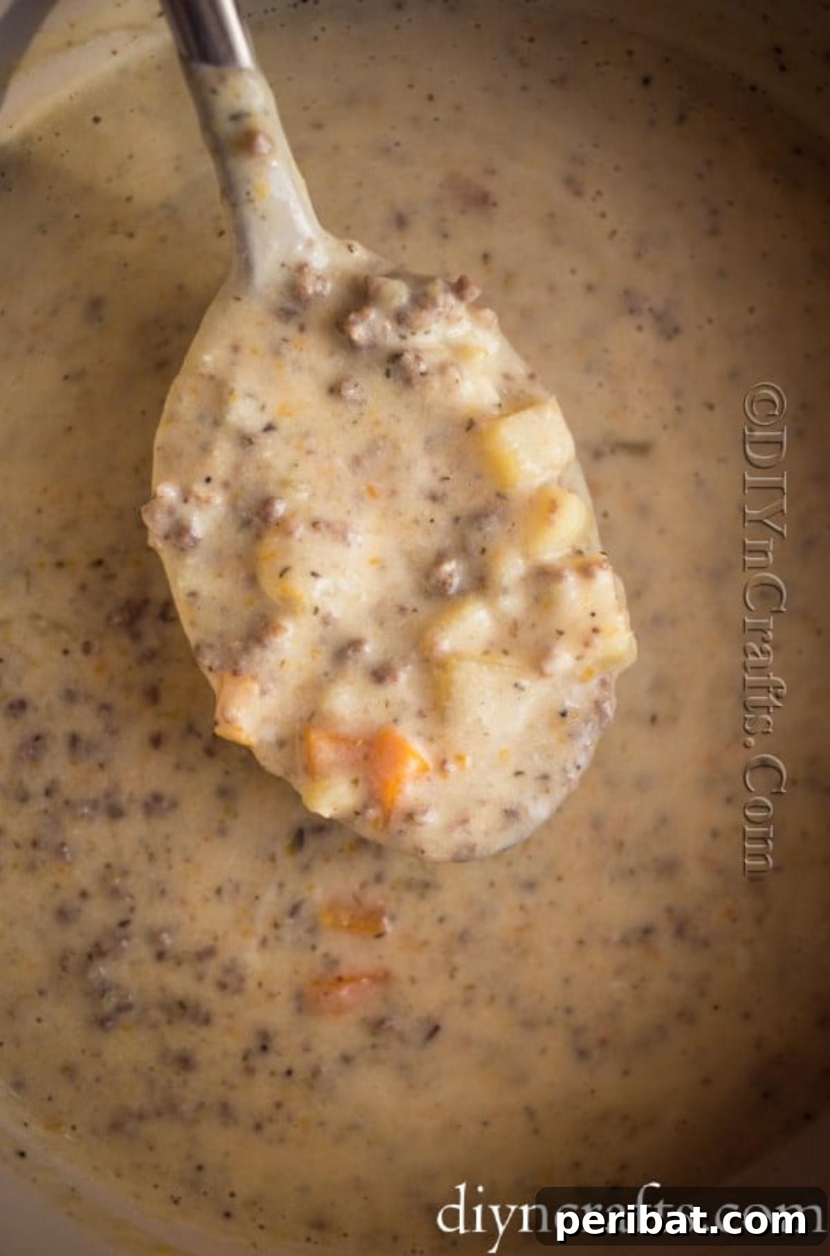 Hearty Family Cheeseburger Soup 7 All the cooked ingredients – vegetables, ground beef, and cheese sauce – being gently mixed together in a large pot to form the complete cheeseburger soup.