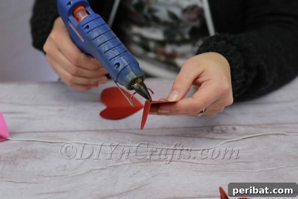 Applying hot glue to paper heart for 3D effect
