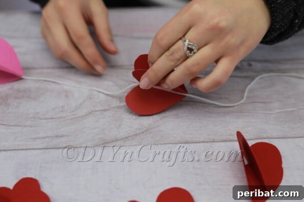Attaching first half of paper heart to string