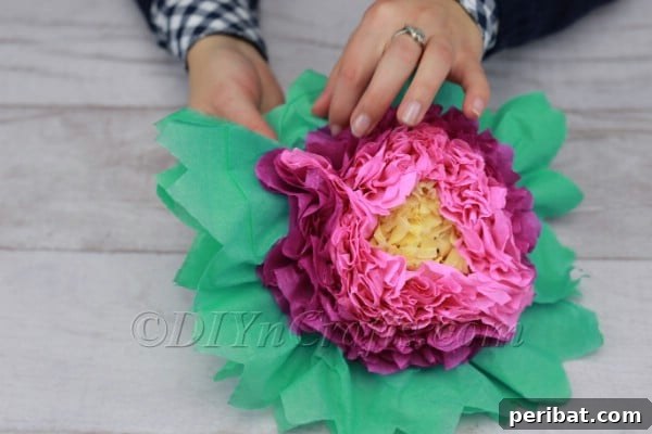 Finished tissue paper flower being arranged, with petals and leaves fluffed