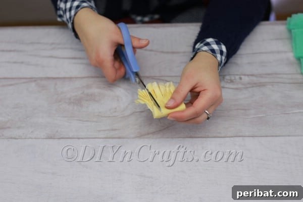 Yellow tissue paper folded and cut with fringes for stamen