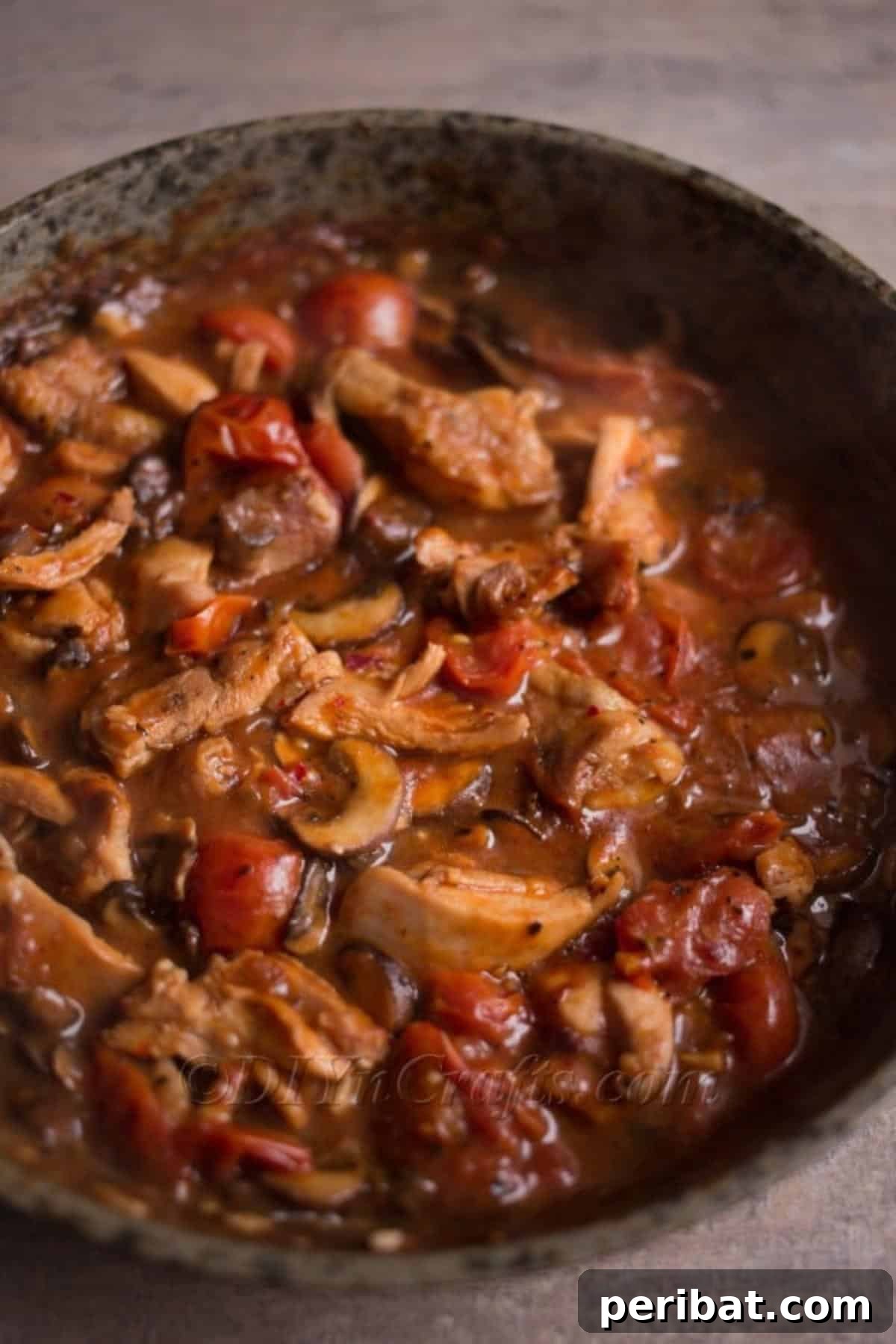 Mixing cooked chicken, mushrooms, and rich tomato sauce.