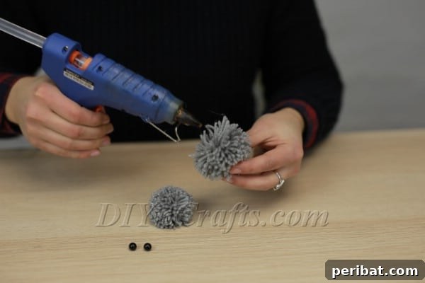 Attaching the two pom-poms together with hot glue