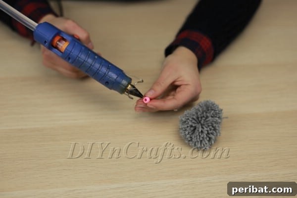 Attaching black beads for eyes onto the pom-pom head