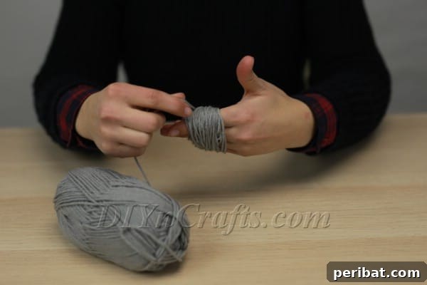 Yarn being spooled around fingers to make a pom-pom
