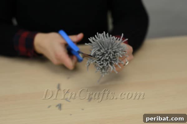 Trimming the pom-pom to achieve a neat, round shape