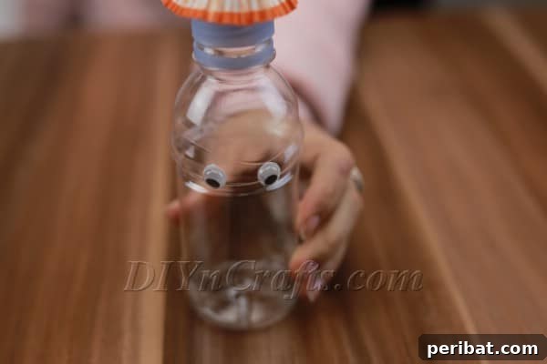 Googly eyes attached to the bottle, beginning to form the face