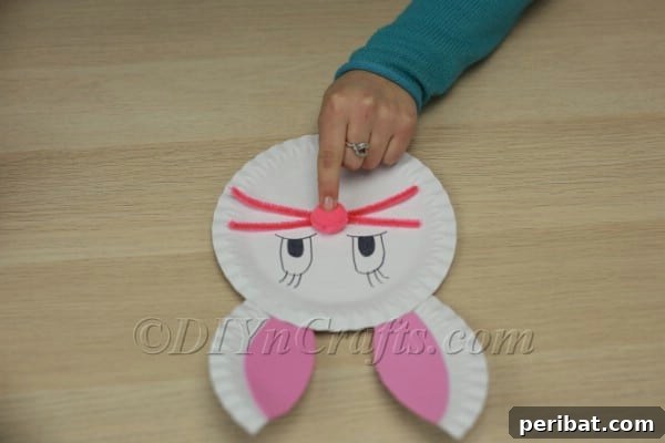 Three Adorable Easter Bunny Crafts Using Paper Plates 22 Gluing a pink pom-pom as the bunny's nose