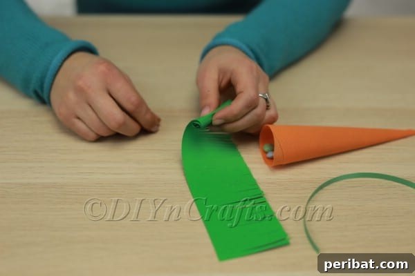 The fringed green strip of fabric or paper being rolled tightly from one end.