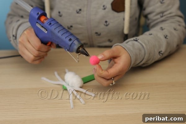 Step 4: Hot gluing the pink pom-pom directly above the white cheeks for the bunny nose