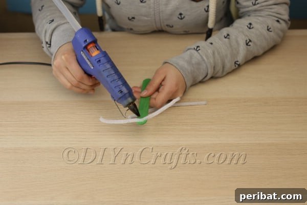 Step 2: Hot gluing the crisscrossed pipe cleaner whiskers onto the craft stick base