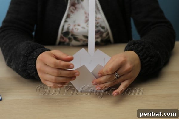 Stapling the second end of the handle to complete the paper Easter basket structure.
