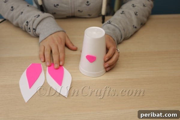 Gluing pink nose onto upside-down Styrofoam cup