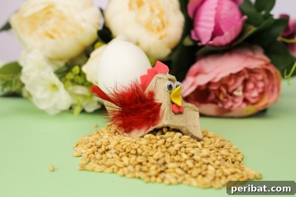 A completed Easter hen craft made from an egg carton, holding a decorative egg.