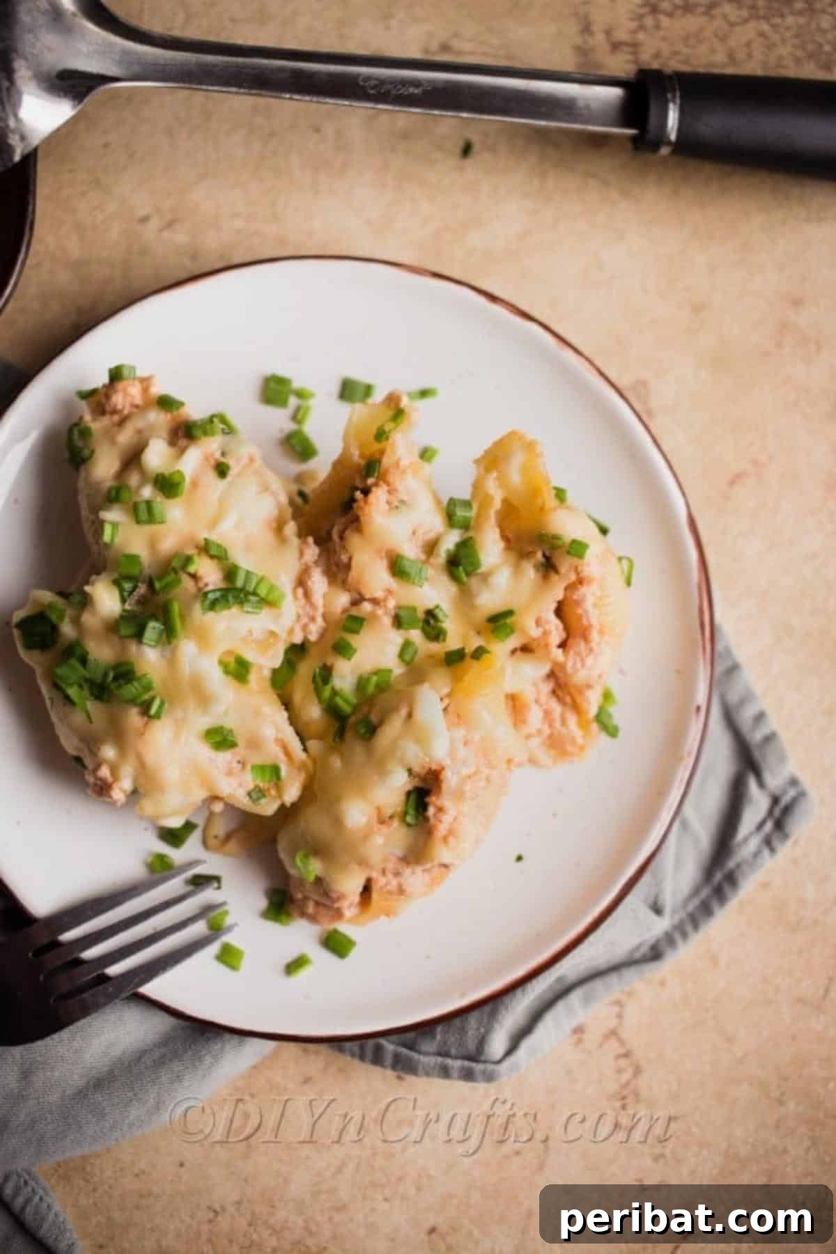 A hand reaching for a serving of hot chicken stuffed pasta shells on a plate.