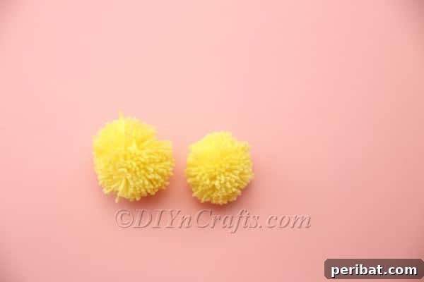 Two finished yellow pom-poms, one for head and one for body
