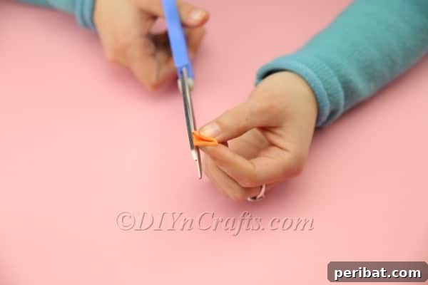 Cutting a small beak shape from orange foam sheet