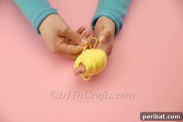 Craft Adorable Pom-Pom Easter Chicks at Home 5 Wrapping yellow yarn around fingers for pom-pom