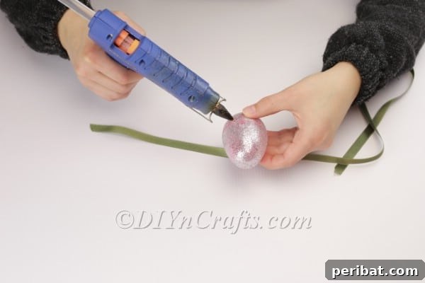 Transform Your Plastic Eggs: Easter Decor DIY 12 Attaching the ribbon to the middle of the plastic egg.