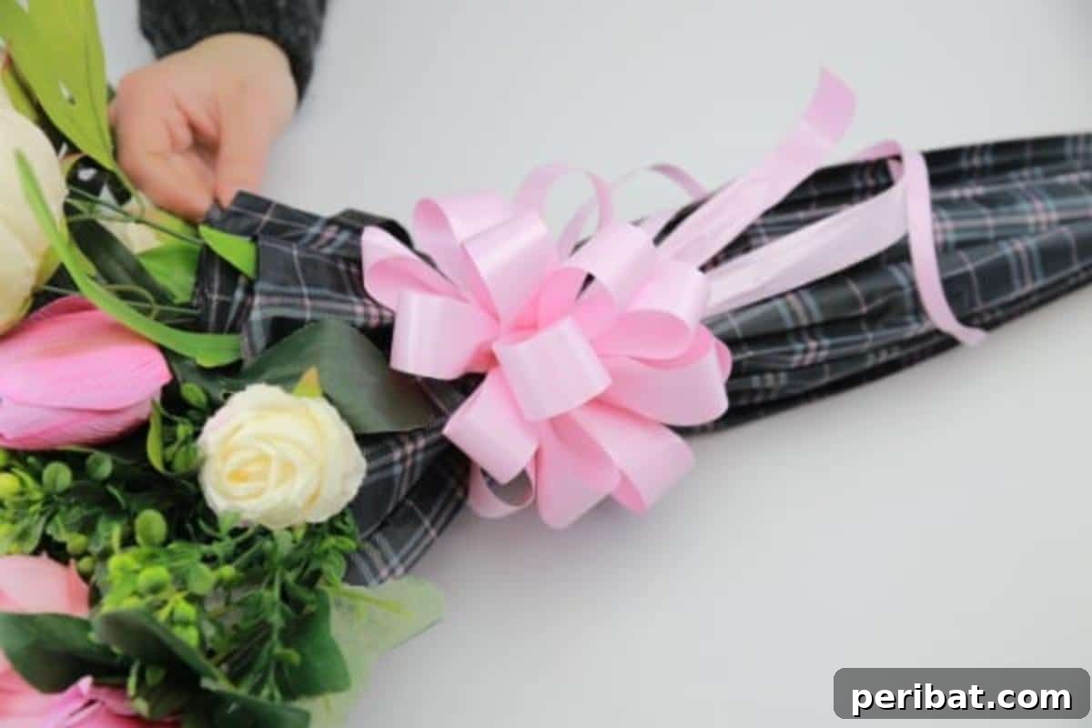 Attaching the beautifully crafted ribbon bow to the umbrella flower arrangement.