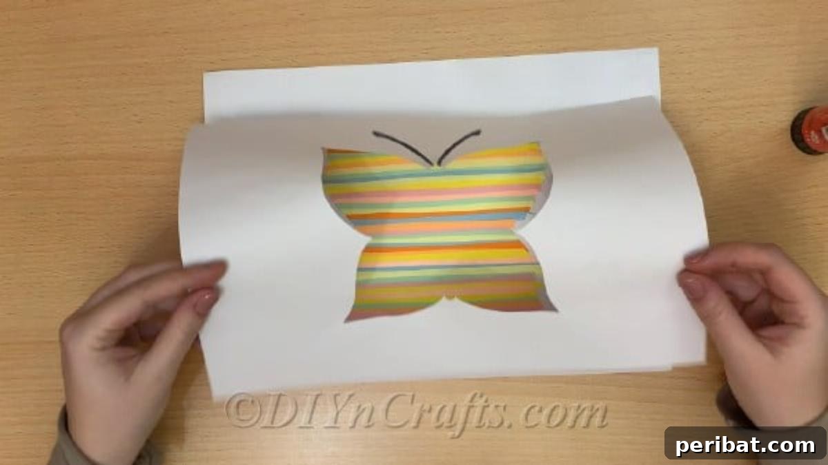 Springtime Flutter: Colorful Paper Butterflies for Little Hands 7 Gluing the black outline of a butterfly template over vibrantly colored paper strips, revealing the butterfly's body.