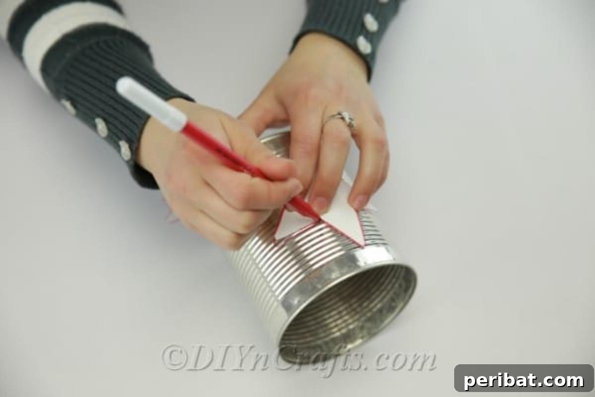 Craft Stunning Lights from Upcycled Tin Cans 8 Tracing a star template onto a tin can with a marker, a crucial step for DIY luminary creation.